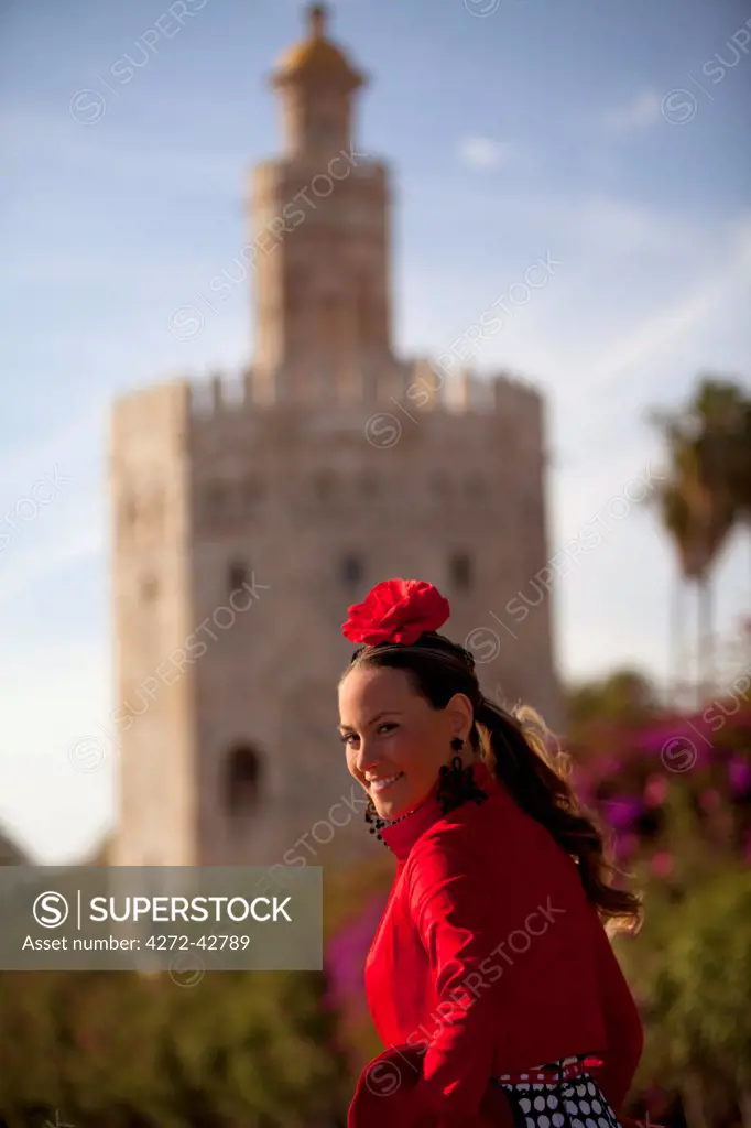 Seville, Andalusia, Spain, A young woman in traditional clothes in front of the Torre del Oro during the Feria de Abril