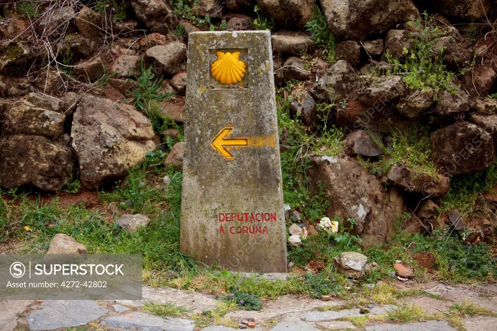 Spain, Galicia, Camino Frances, A typical stone sign on the camino with the shell, indicating the direction and distance from Santiago