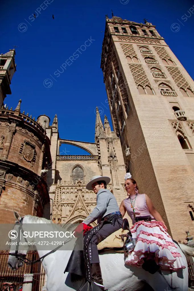Seville, Andalusia, Spain. A horse riding couple from the El Rocio Pilgrimage in front of the Giralda in Seville begining the three day Journey ending in El Rocio in the Heulva region