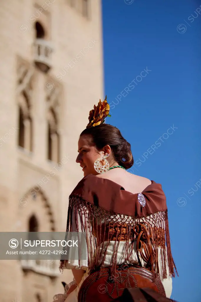 Seville, Andalusia, Spain. A young woman in Flamenco dress a participants of the El Rocio Pilgrimage in front of the Giralda in Seville leaving for the three day Journey ending in El Rocio in the Heulva region