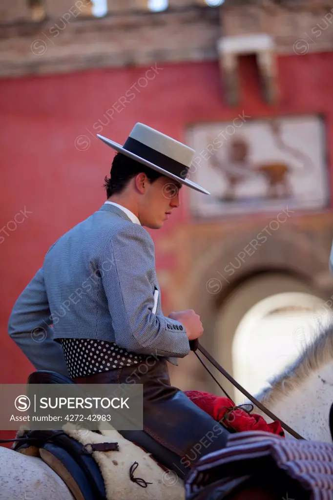 Seville, Andalusia, Spain. A young man in cowboy traditional Andalusian attire a participant of the El Rocio Pilgrimage riding in front of the gate to the Alcazar leaving Seville for the three day Journey ending in El Rocio in the Heulva region