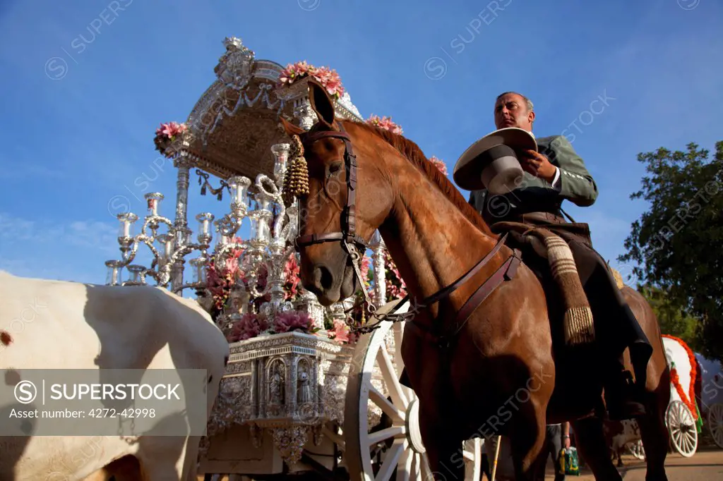 Seville, Andalusia, Spain. Man in traditional cowboy clothes on horseback during a prayer at a visit outside one of the chapels in the countryside on the way to the village of El Rocio during the El Rocio pilgimage