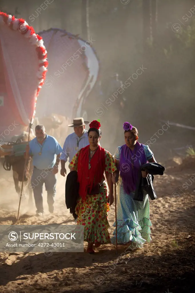 Huelva, Southern Spain. Two woman walk with Carriages in the background during the El Rocio pilgrimage on their way to the village of El Rocio