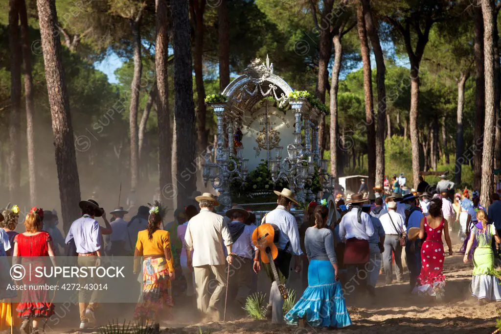 Huelva, Southern Spain. Pilgrims walking through the woods with the float of the Madonna on their way to the village of El Rocio during the annual Romeria