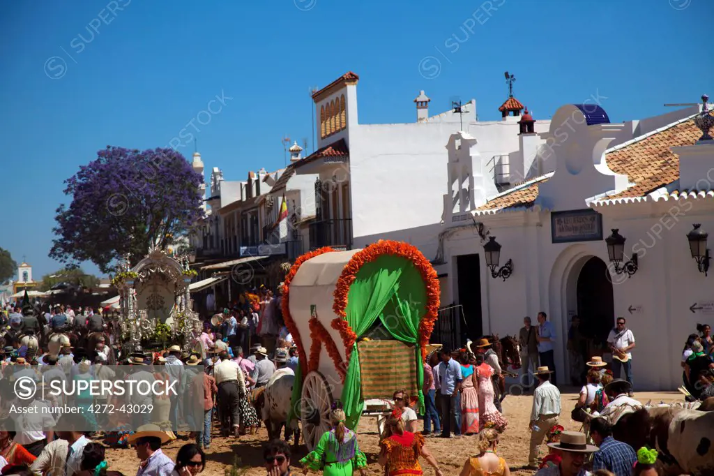 El Rocio, Huelva, Southern Spain. Wagon carried amidst people walking in traditional clothes and whitewashed buildings in the village of El Rocio during the annul Romeria