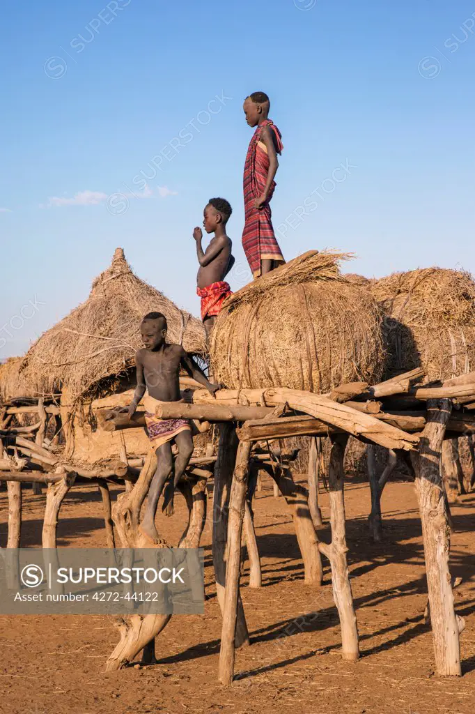 Dassanech boys on the platform of a granary, Ethiopia