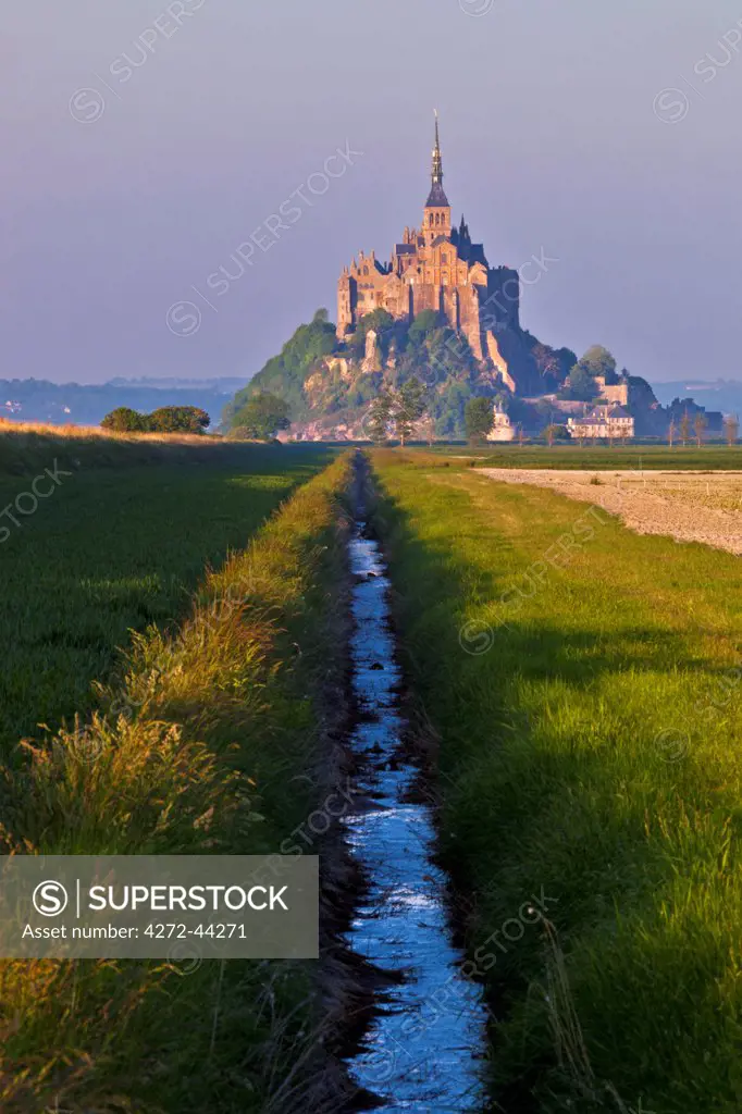 Mont Saint Michel  at sunset viewed from a polder and a drainage channel, Le Mont Saint Michel, Basse Normandie, France.