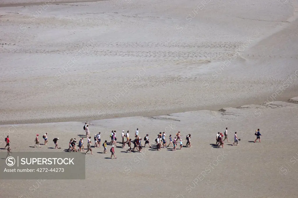 Tourists cross the tidal basin at low tide in front of Le Mont Saint Michel, Basse Normandie, France.