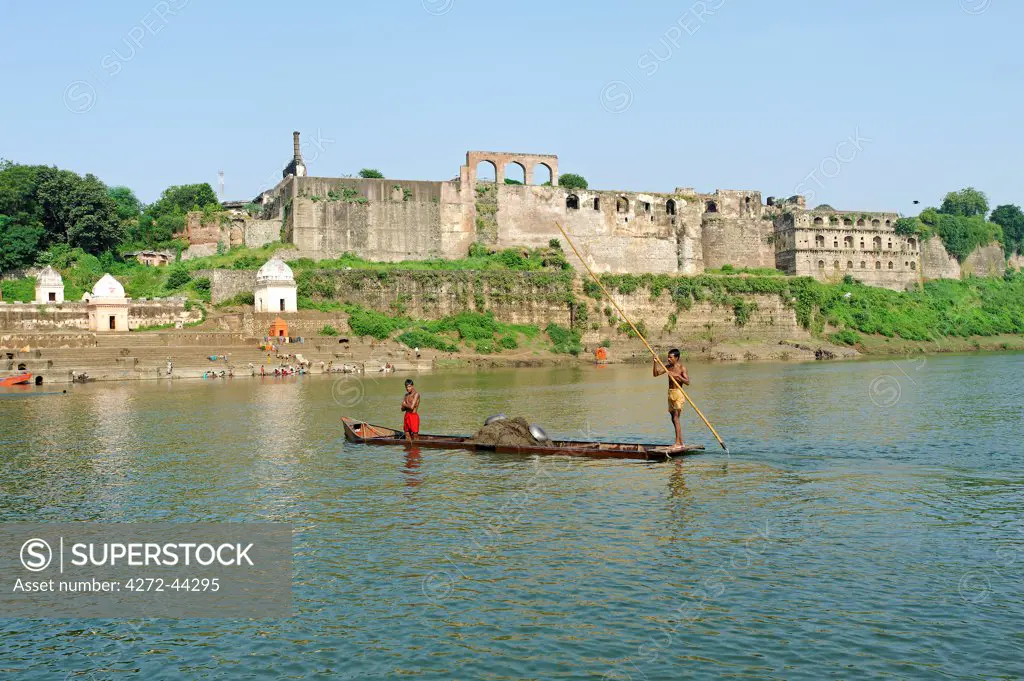 India, Madhya Pradesh, Burhanpur. Boatmen punt in the Tapti River beside the Shahi Qila, a medieval palace.