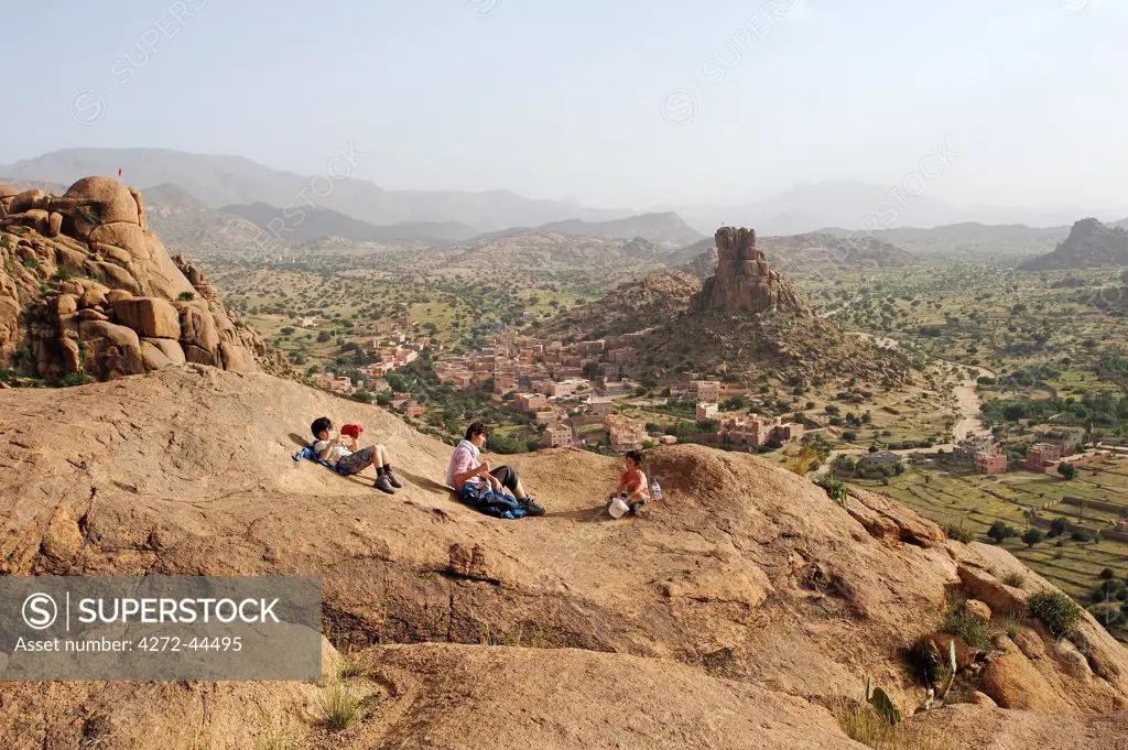 Morocco, Anti Atlas Mountains, Tafraoute, Aguard Oudad. A family rest in the hills above the Berber village of Aguard Oudad with the rock formation known as Napoleon's Hat behind.