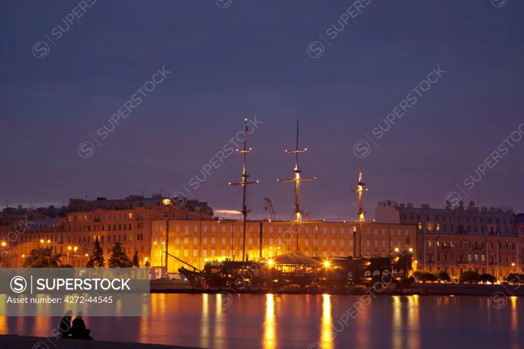Russia, St.Petersburg. Couple on the bank of Vasilevski island onlooking the spectacular scene during the White nights