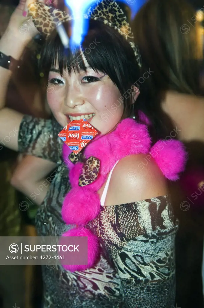 China, Beijing. A girl dancing with a Love condom in her mouth at the International Halloween Party at the Arena nightclub.