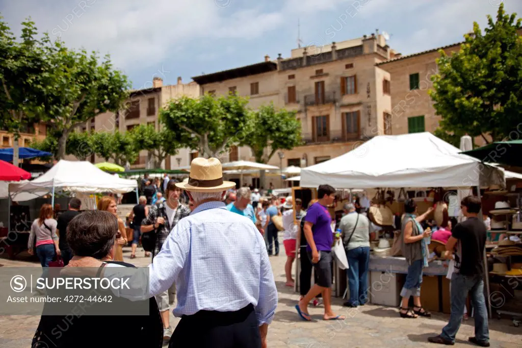 Mallorca, Pollenca. An elderly couple make their way through a busy market square.