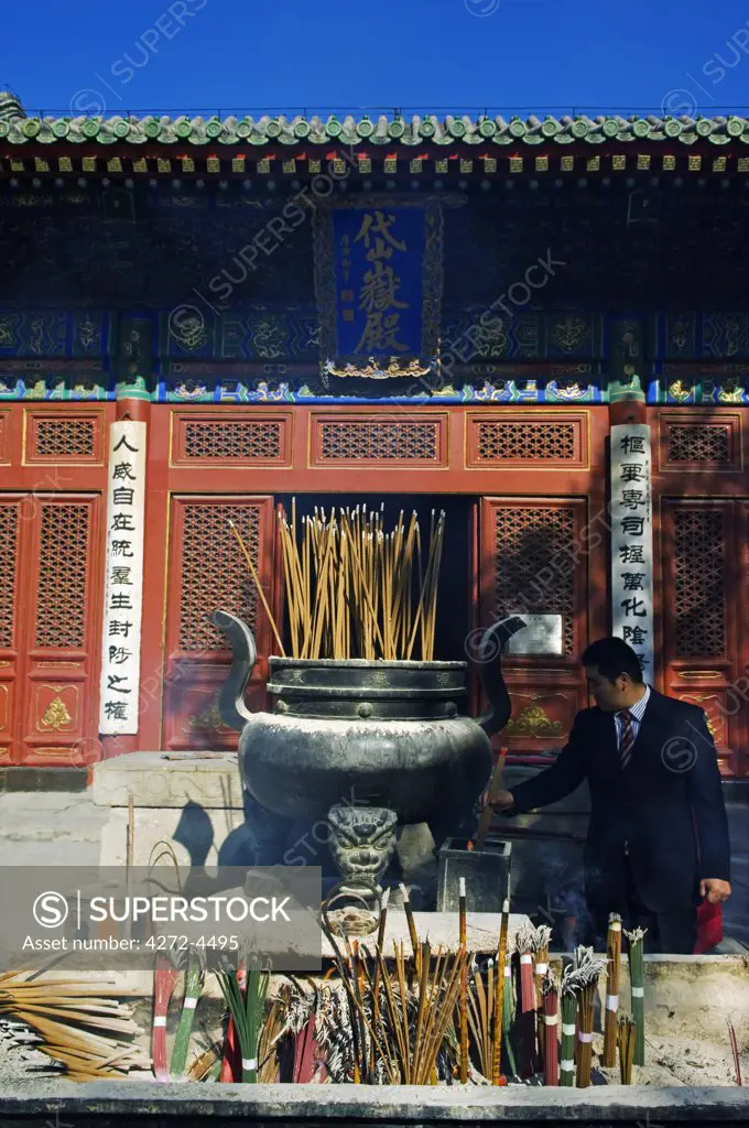 China, Beijing, Donyue temple. A business man visiting the Taoist temple to burn incense.