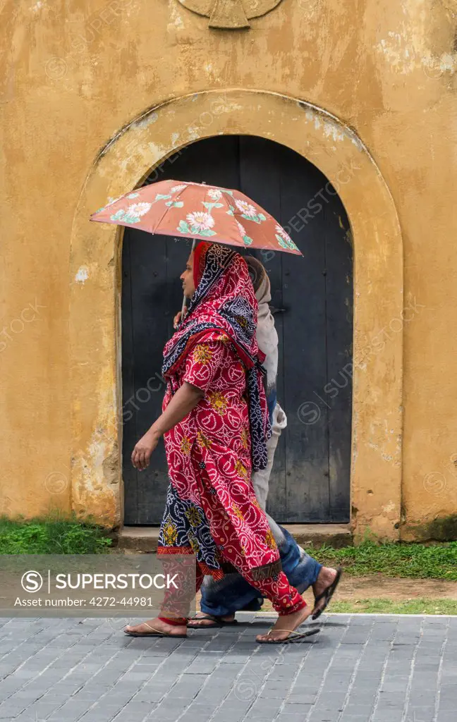 Two women walk past an ancient Dutch East India Company warehouse in Galle Fort, Sri Lanka