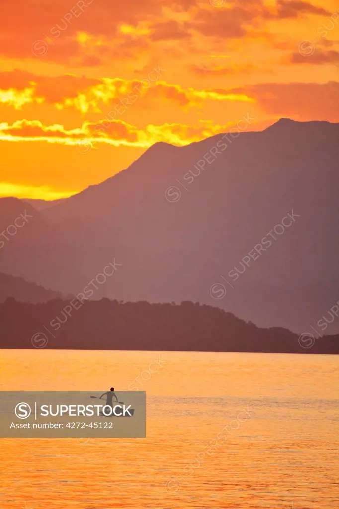 Brazil, Rio de Janeiro State, Angra dos Reis, Ilha Grande, a fisherman silhouetted against the sunset over the Costa Verde, Green Coast,
