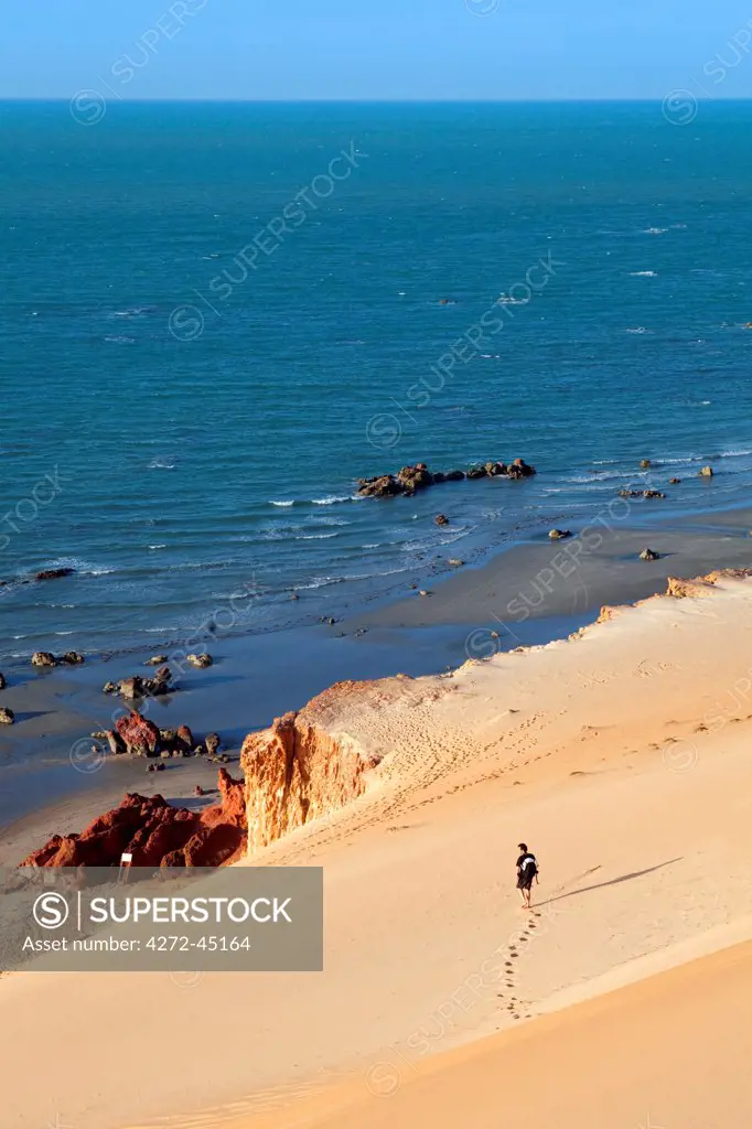 South America, Brazil, Ceara, Morro Branco, a photographer looks out over a long sandy beach and the Atlantic Ocean from the summit of the dunes MR