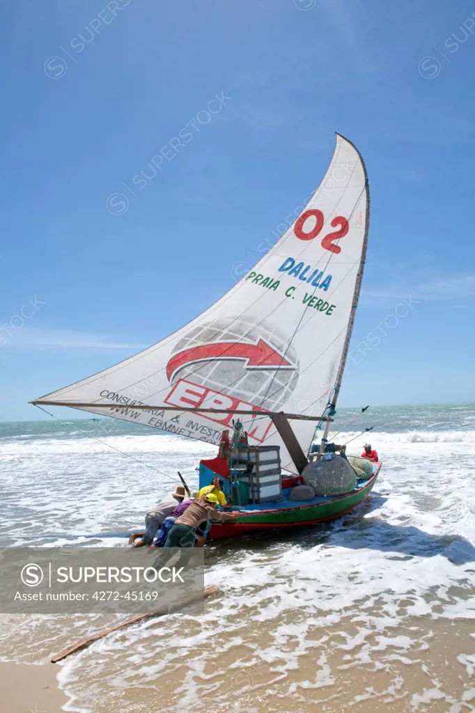 South America, Brazil, Ceara, Fortaleza, fishermen launching a jangada on the beach in the Prainha do Canto Verde Extractivist Reserve, Reserva Extrativista da Prainha do Canto Verde,. The jangada is said to be the only slightly modified descendant of the boats used by Odysseus
