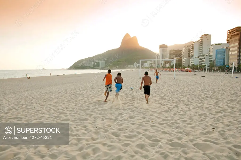 South America, Rio de Janeiro, Rio de Janeiro city, Ipanema, boys playing football on Ipanema beach in front of the Dois Irmaos mountains