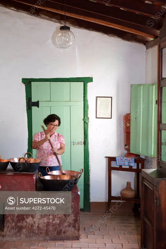 South America, Brazil, Goias, Cidade de Goias, A woman stirring a traditional copper pot on a Brazilian wood fired stove in the Casa Cora Coralina museum in Old Goias, MR,  PR