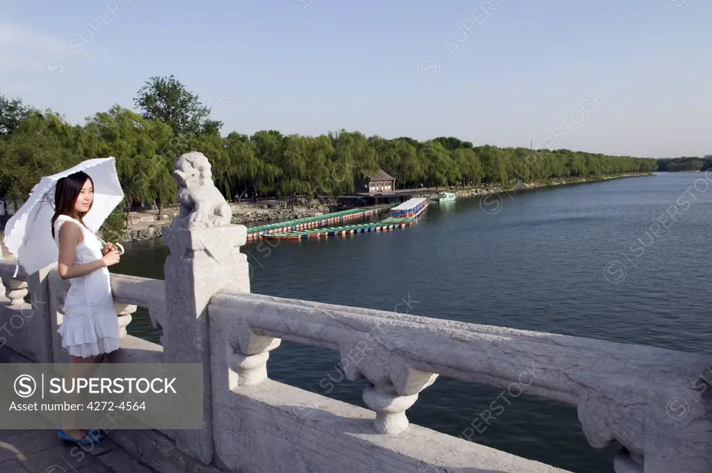 China, Beijing. Summer Palace Unesco World Heritage Site. A young girl on the 17 arch bridge (MR).