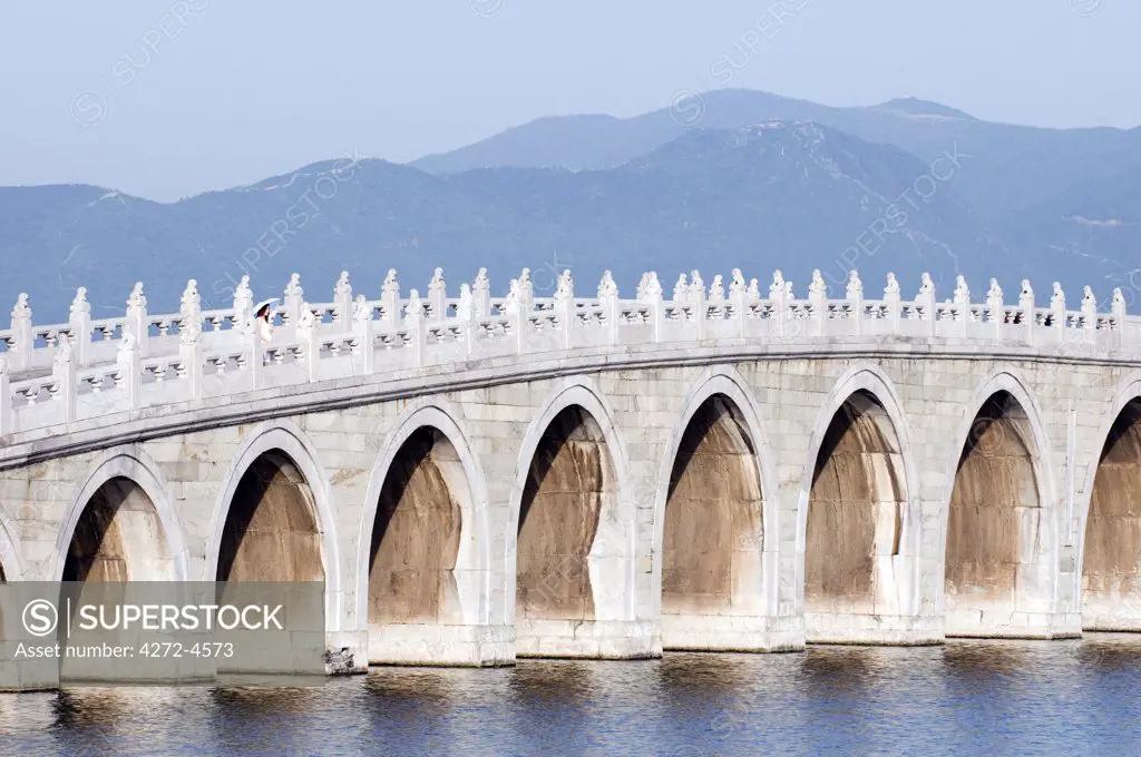 China, Beijing. Summer Palace - Unesco World Heritage Site. A young girl on the 17 arch bridge (MR)