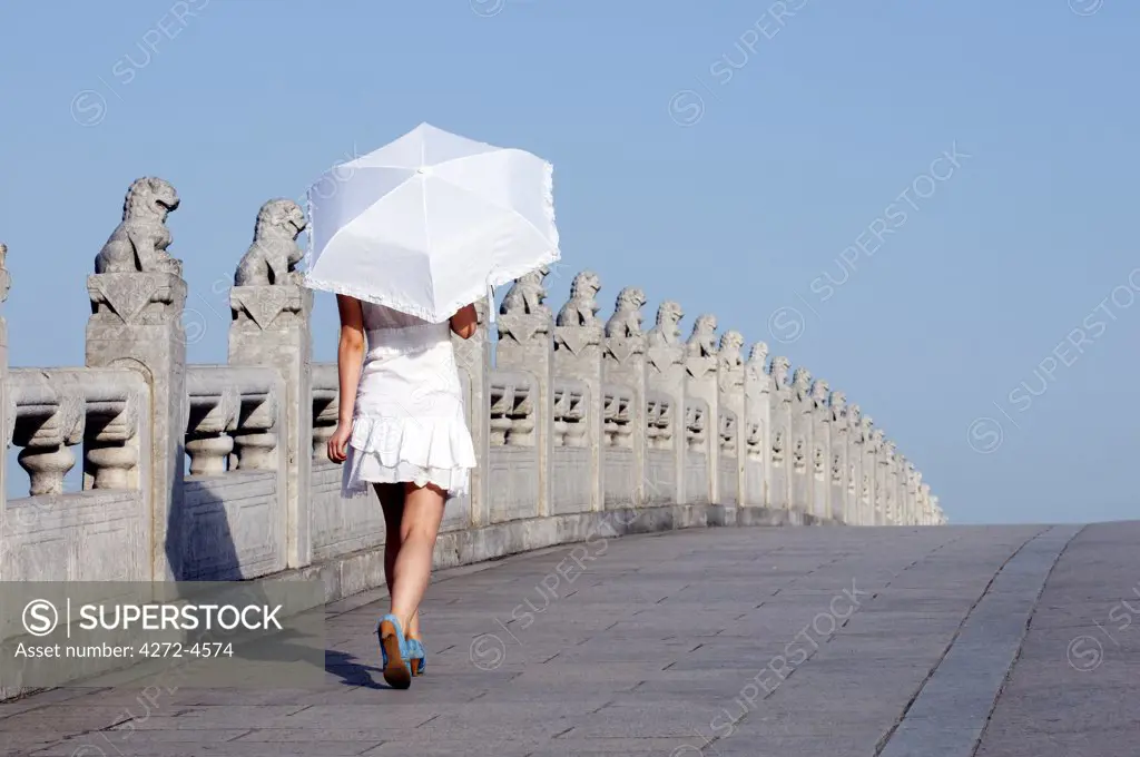 China, Beijing. Summer Palace - Unesco World Heritage Site. A young girl on the 17 arch bridge (MR).
