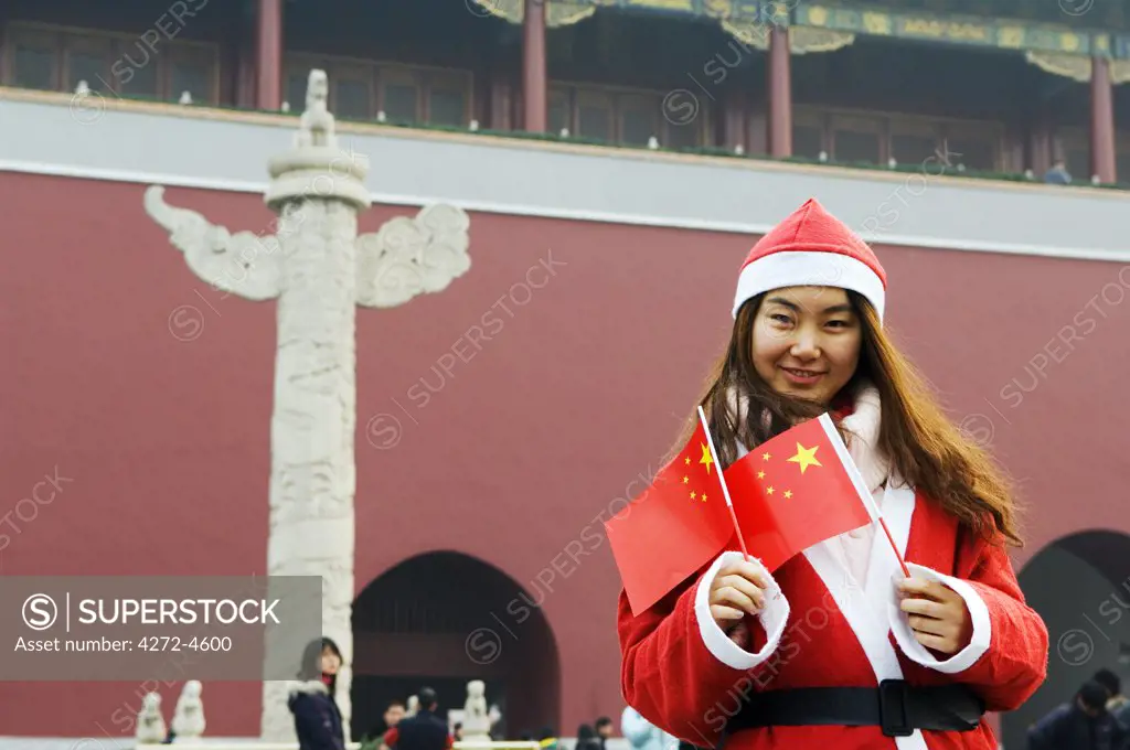 China, Beijing, Tiananmen Square. A Chinese girl dressed up as Santa on Christmas Day (MR).