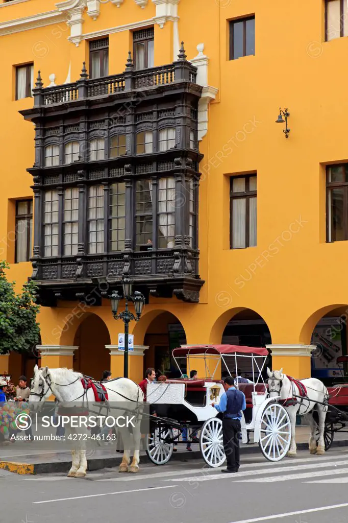 South America, Peru, Lima, a horse and carriage stand in front of a wooden balcony window on the Union Club situated on the main square in the colonial city centre