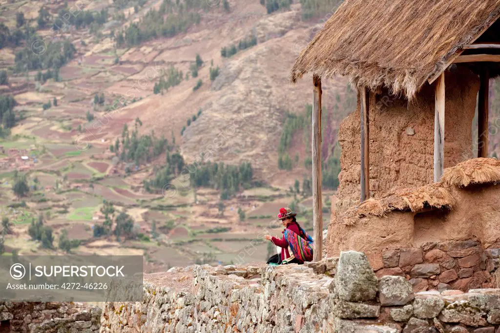 South America, Peru, Cusco, Sacred Valley, Pisac. A Quechua woman in a montera hat and with a Keperina shawl looks out over the Sacred Valley from the hills above Pisac