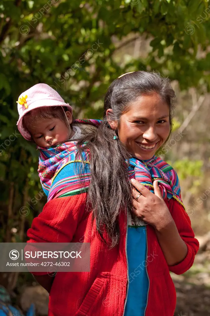 South America, Peru, Cusco, Yanama. A Quechua woman from Yanama village in the high Andes with a baby wrapped in a Keperina shawl