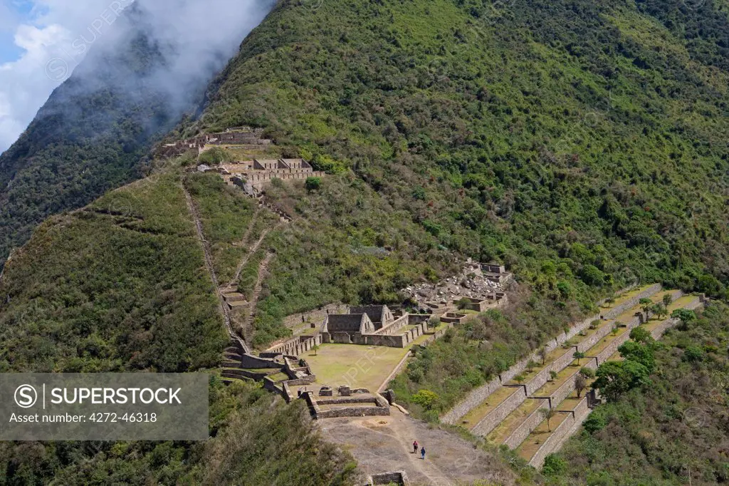 South America, Peru, Cusco, Choquequirao. Terraces, plazas and buildings at the Inca city of Choquequirao built by Tupac Inca Yupanqui and Huayna Capac and situated above the Apurimac valley with mountains of the Salkantay range with hikers in the foreground