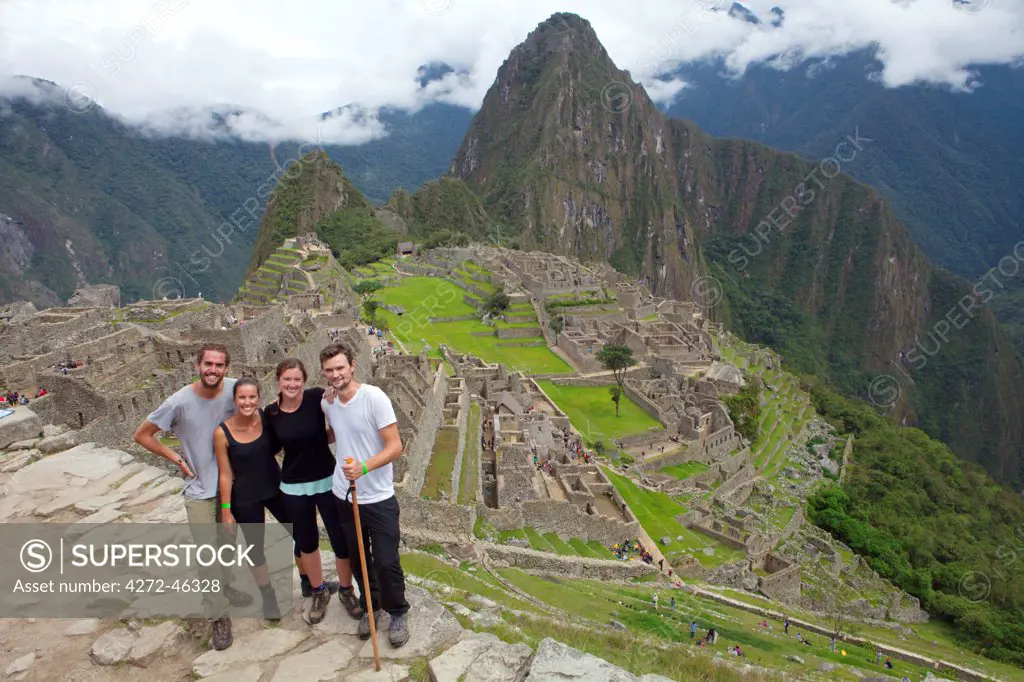 South America, Peru, Cusco, Machu Picchu. Inca trail hikers in front of the World Heritage listed Inka Historic Sanctuary of Machu Picchu with Huayna Picchu, Wayna Picchu, mountain behind. The site is situated in the Andes above the Urubamba valley, MR,