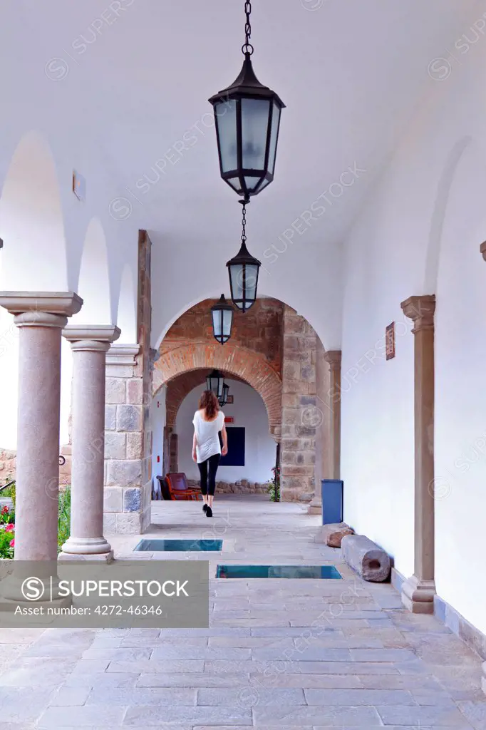 South America, Peru, Cusco, a model walks along a cloister corridor in the Orient Express Palacio Nazarenas hotel, housed in a former Spanish convent, PR,, MR,