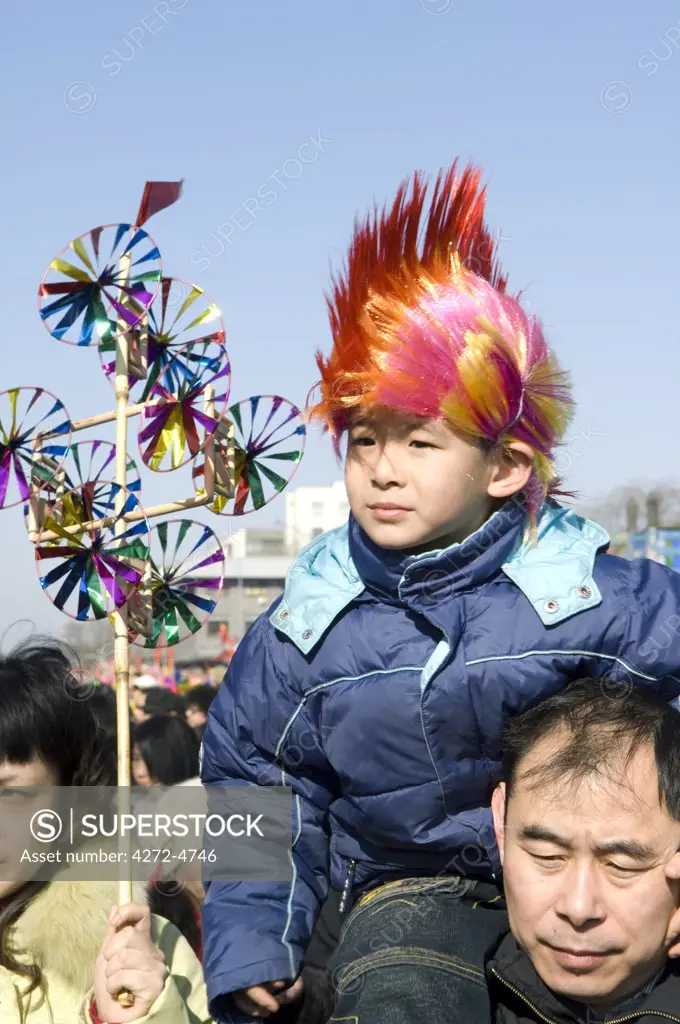 China, Beijing. Chinese New Year Spring Festival - Changdian street fair - a man carrying his child with a wind vane toy.