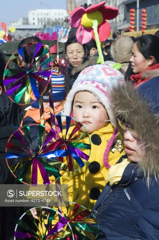 China, Beijing. Chinese New Year Spring Festival - Changdian street fair - a man carrying his child with a wind vane toy