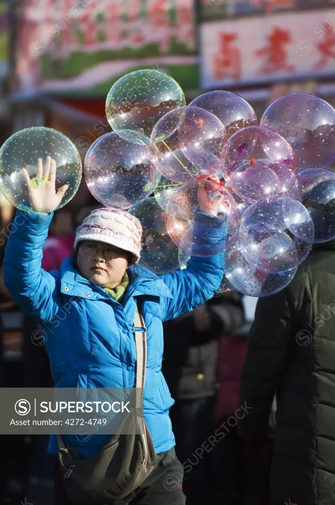 China, Beijing. Chinese New Year Spring Festival - a girl selling balloons at Changdian street fair