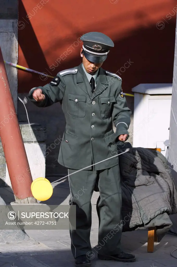 China, Beijing. Chinese New Year Spring Festival - a security guard playing with a Diabolo toy at Changdian street fair.