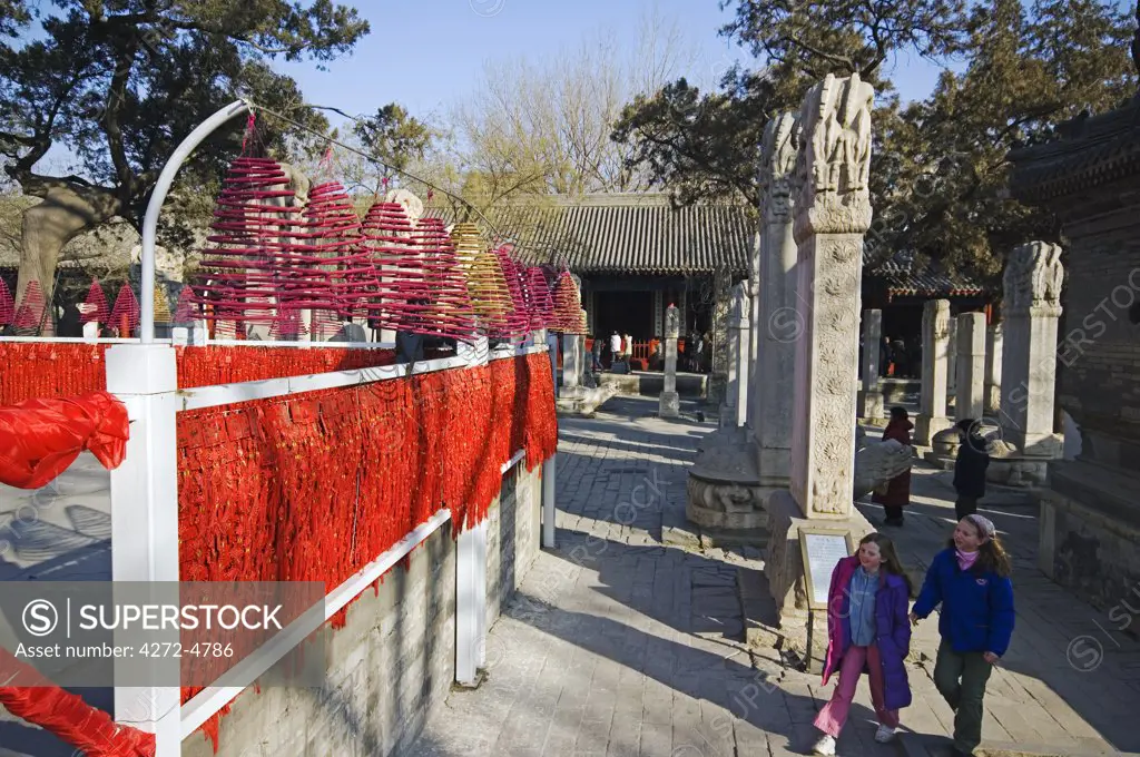 China, Beijing. Chinese New Year Spring Festival - two foreign children walking past incense and good luck offerings at Donyue temple and Beijing Folk Arts Museum.