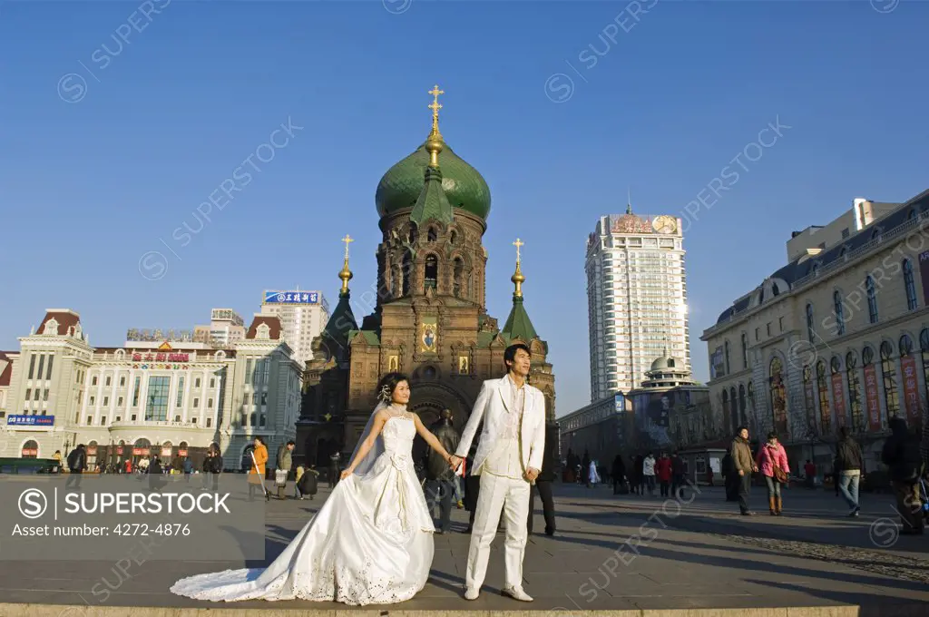 China, Northeast China, Heilongjiang Province, Harbin City. A wedding couple pose for photos in the middle of winter in front of St Sophia Russian Orthodox Church built in 1907 in the Daoliqu area.