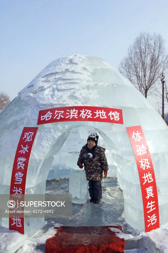 China, Northeast China, Heilongjiang Province, Harbin City. Snow and Ice Sculpture Festival at Sun Island Park. A young boy inside an ice igloo.