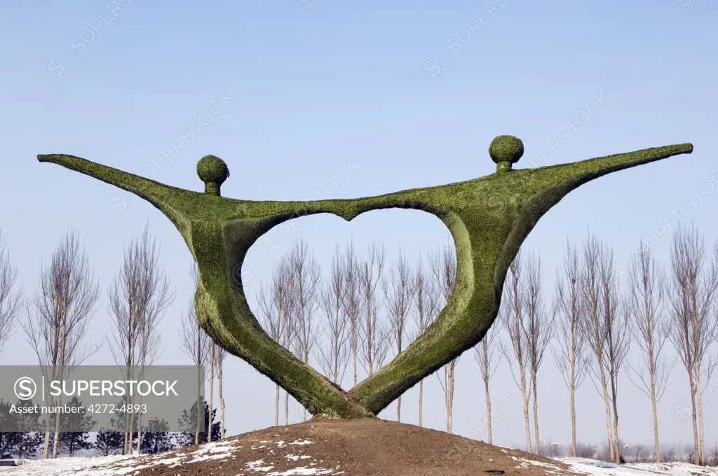 China, Northeast China, Heilongjiang Province, Harbin City. Snow and Ice Sculpture Festival at Sun Island Park. A modern art sculpture statue of two people holding hands in heart shape.