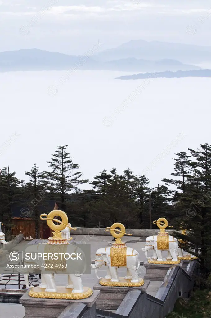 China, Sichuan Province, Mt Emei Unesco World Heritage site. Elephant statues at the Golden Summit temple and an early morning sea of clouds