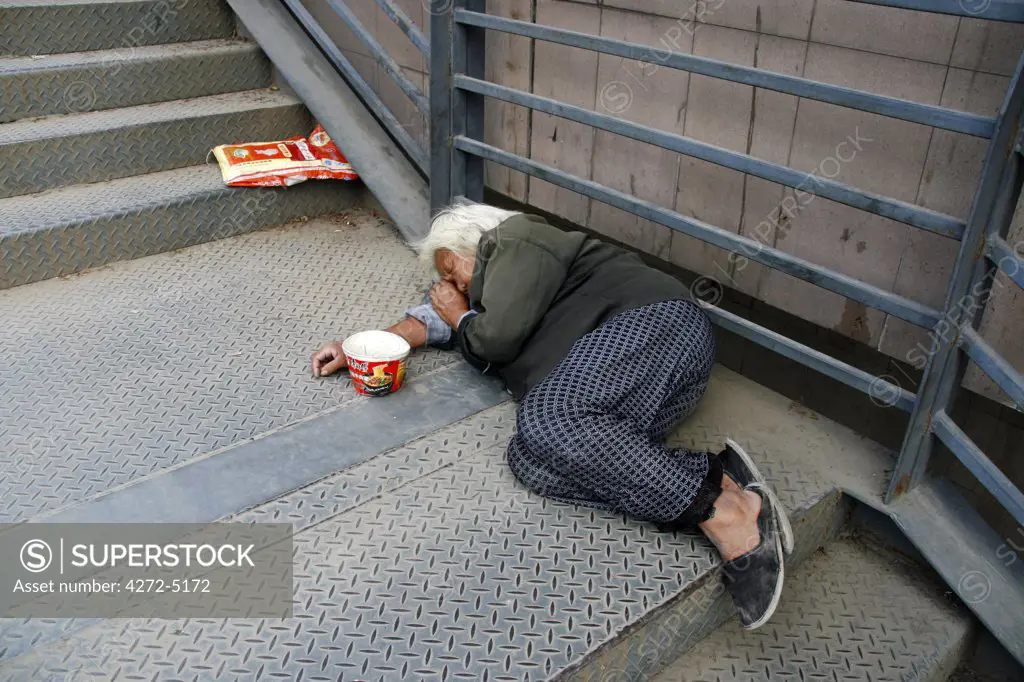 China, Shanghai. Beggar sleeping on the street in Shanghai.