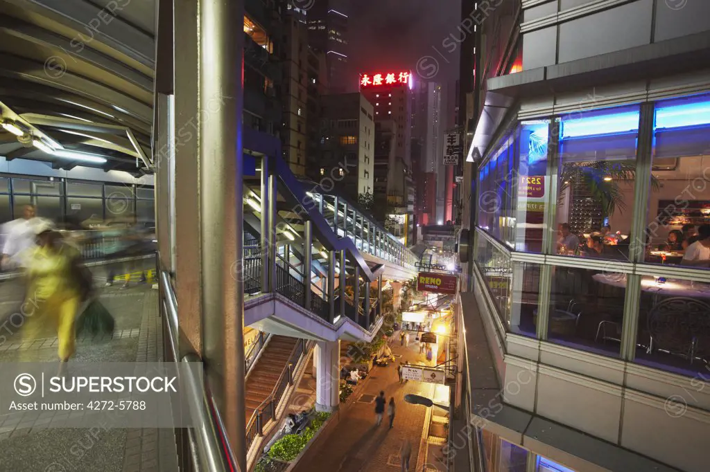 People walking past restaurants of Soho on Mid-Levels escalator at night, Central, Hong Kong, China