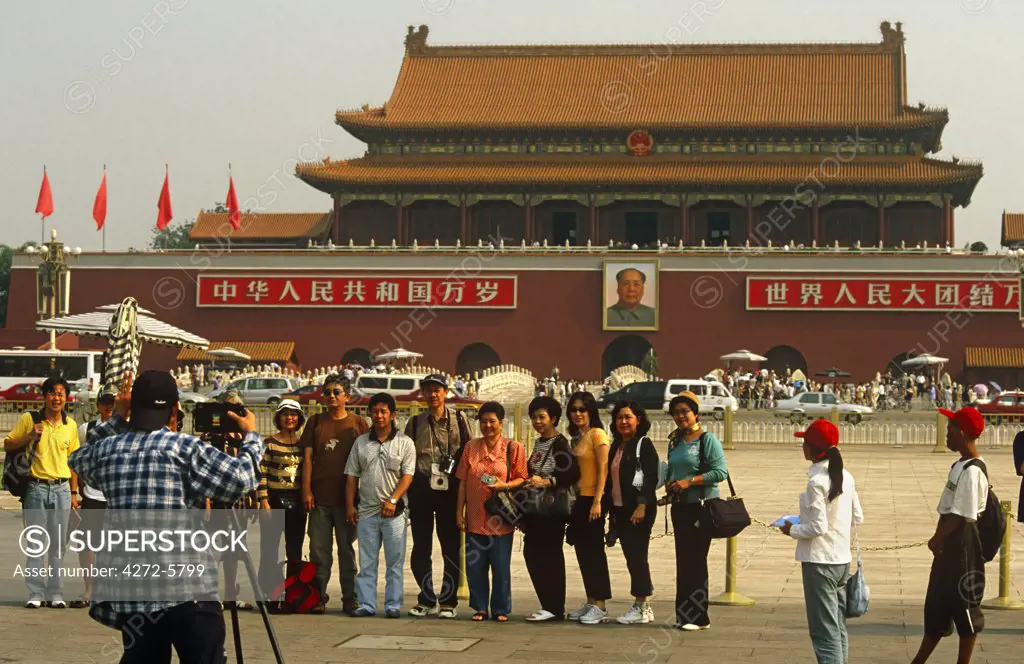 China, Beijing. Tourists at Tian'anmen Sqaure pose before the Tian'anmen Gate entrance to the Forbidden City.