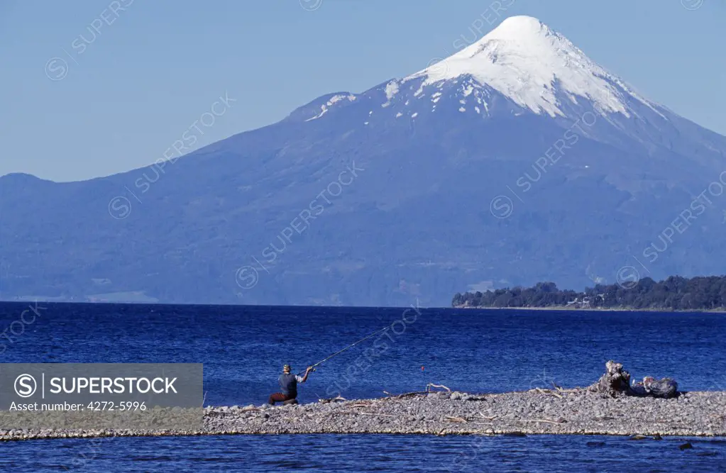 Chile, Lake District. Fisherman on Lago Llanquihue with Volcano Osorno behind