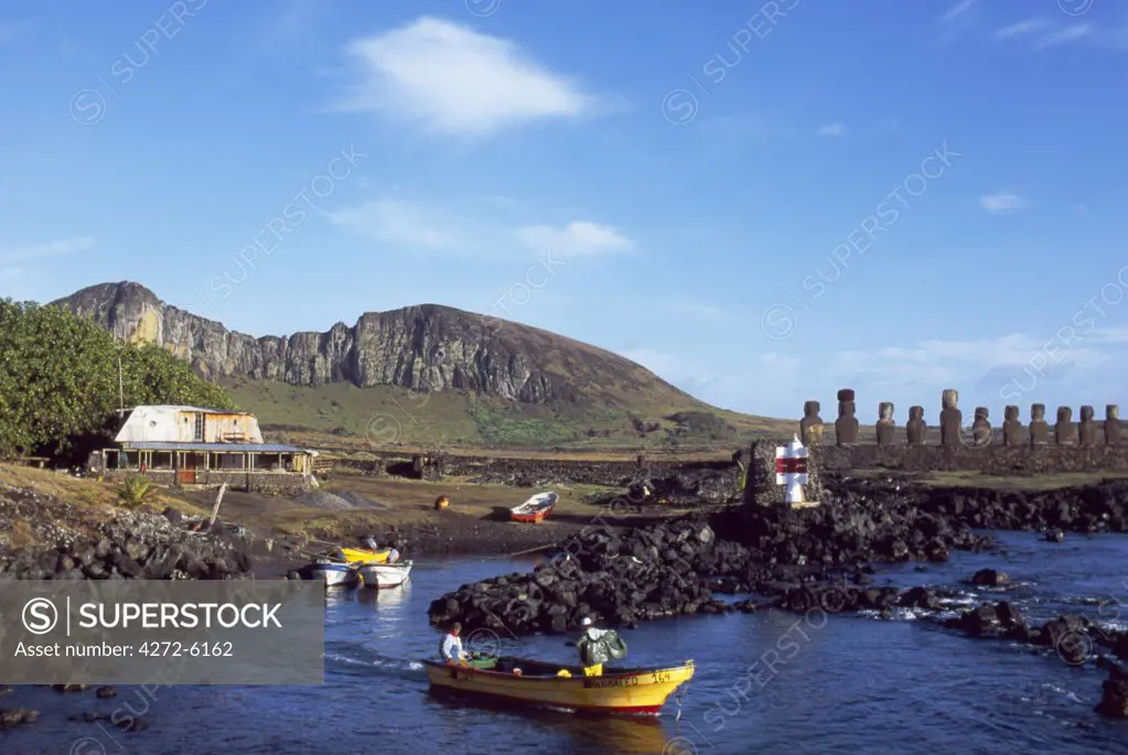 Fishermen prepare to head out from the small harbour at Tongariki with the outline of Rano Roraku volcano and the fifteen colossal stone statues or moais of Tongariki in the background.   The moais stand on their platform or ahu on the eastern coast of the island at the foot of the Poike Peninsula.   The vast majority of Easter Islands 800 moais were chiselled out of the volanic tuff on the side of Rano Raraku between 700 to 1500AD.