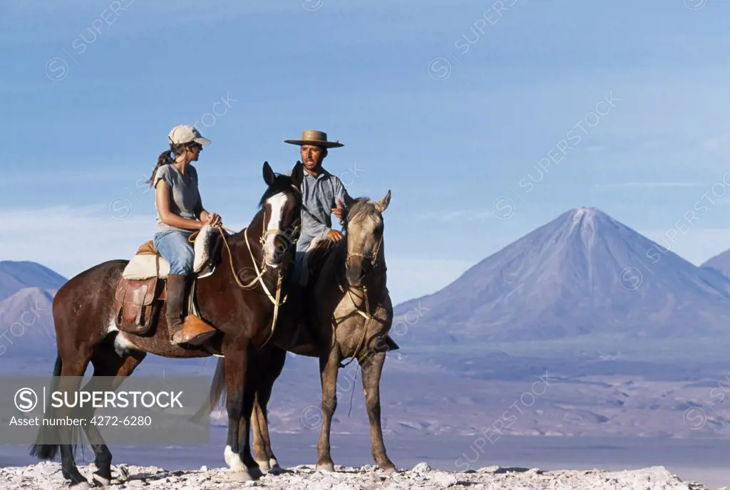 Chatting during a break in a horse trek along Las Cornicas ridge with the perfect cone of Volcan Licancabur in the background