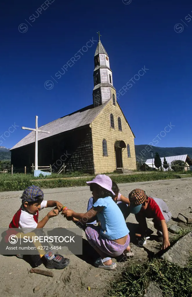 Chile, Region X. Children playing outside a shingled Church in Cochamo.